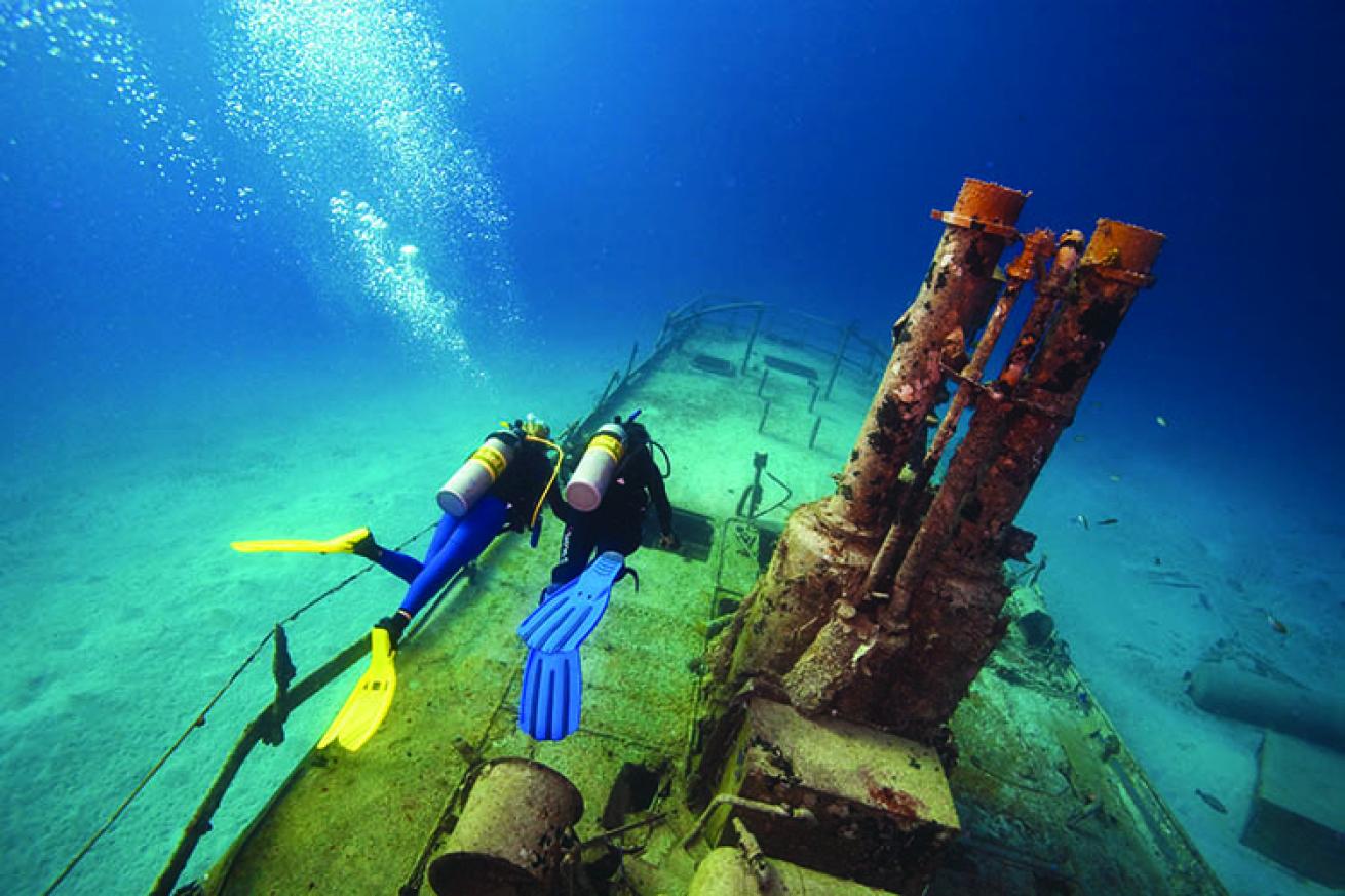 Divers swim over a wreck