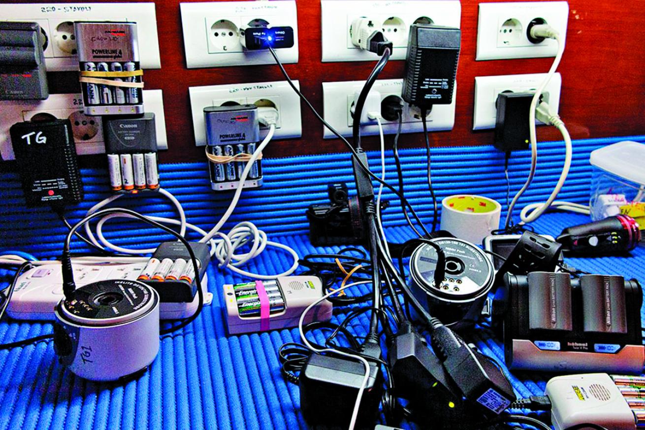 different types of lithium batteries used in underwater cameras and lights plugged in on a desk, which can be dangerous on liveaboard
