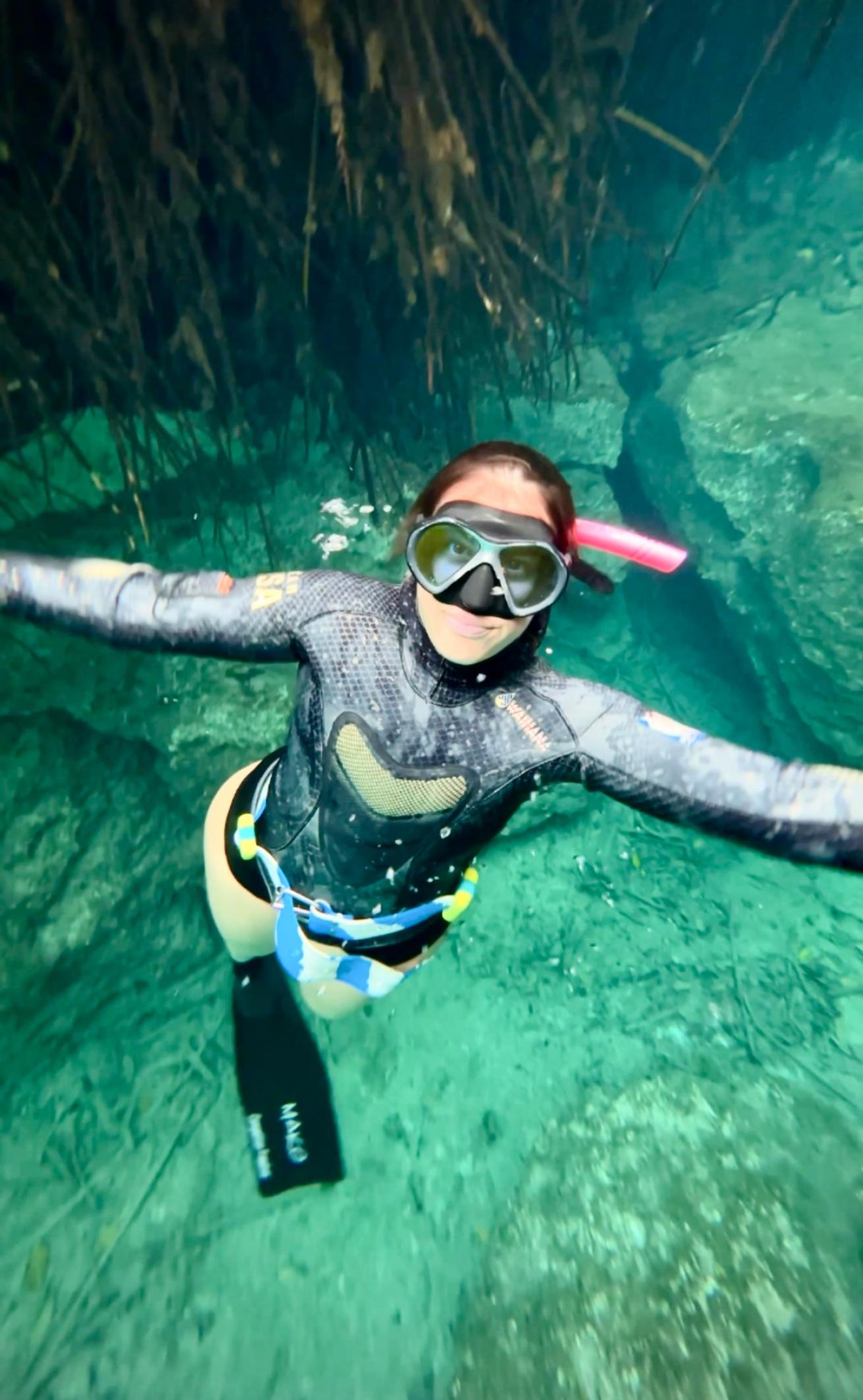 a freediver swims towards the camera in cenote mexico
