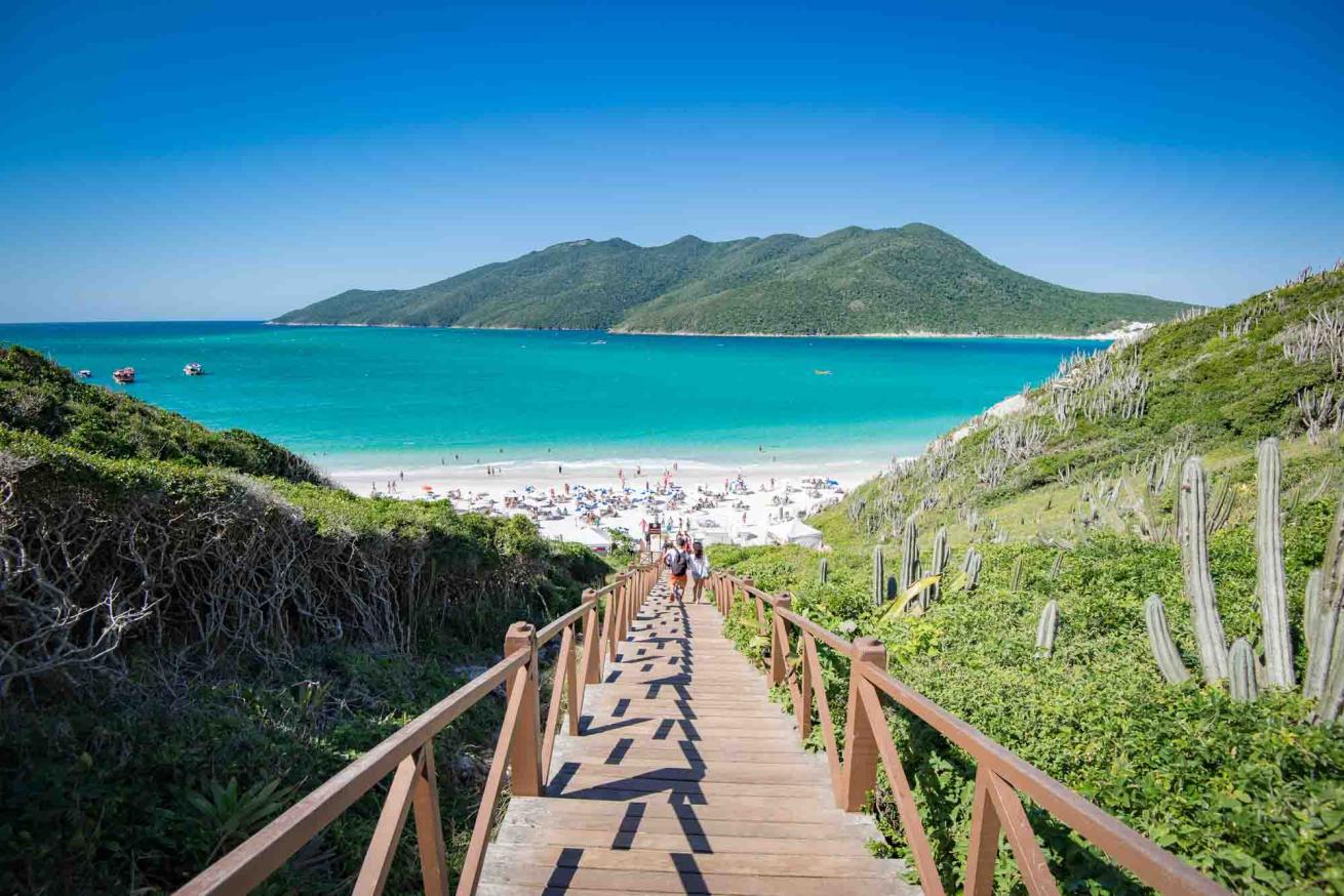 Pontal do Atalaia beach, stairs heading to a white sandy beach with turquoise water and land in the background