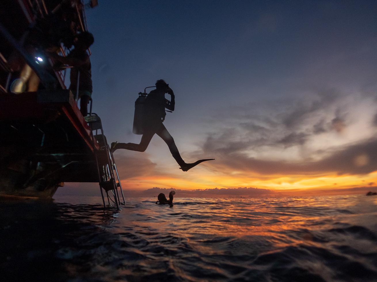 image of a diver entering the water at sunrise