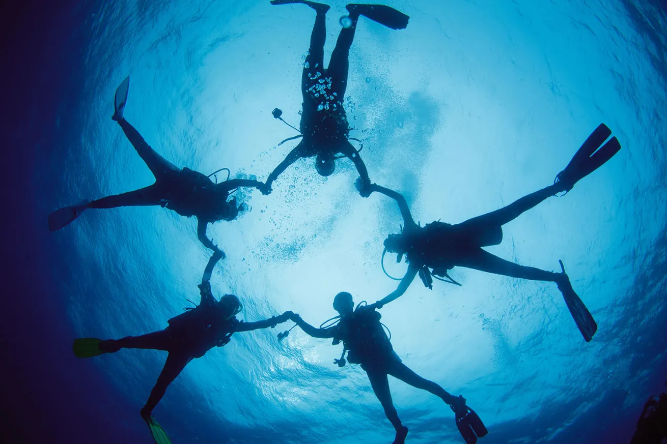 Divers holding hands underwater