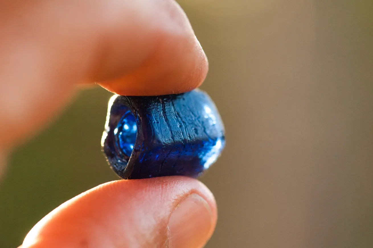 Person holding a blue bead