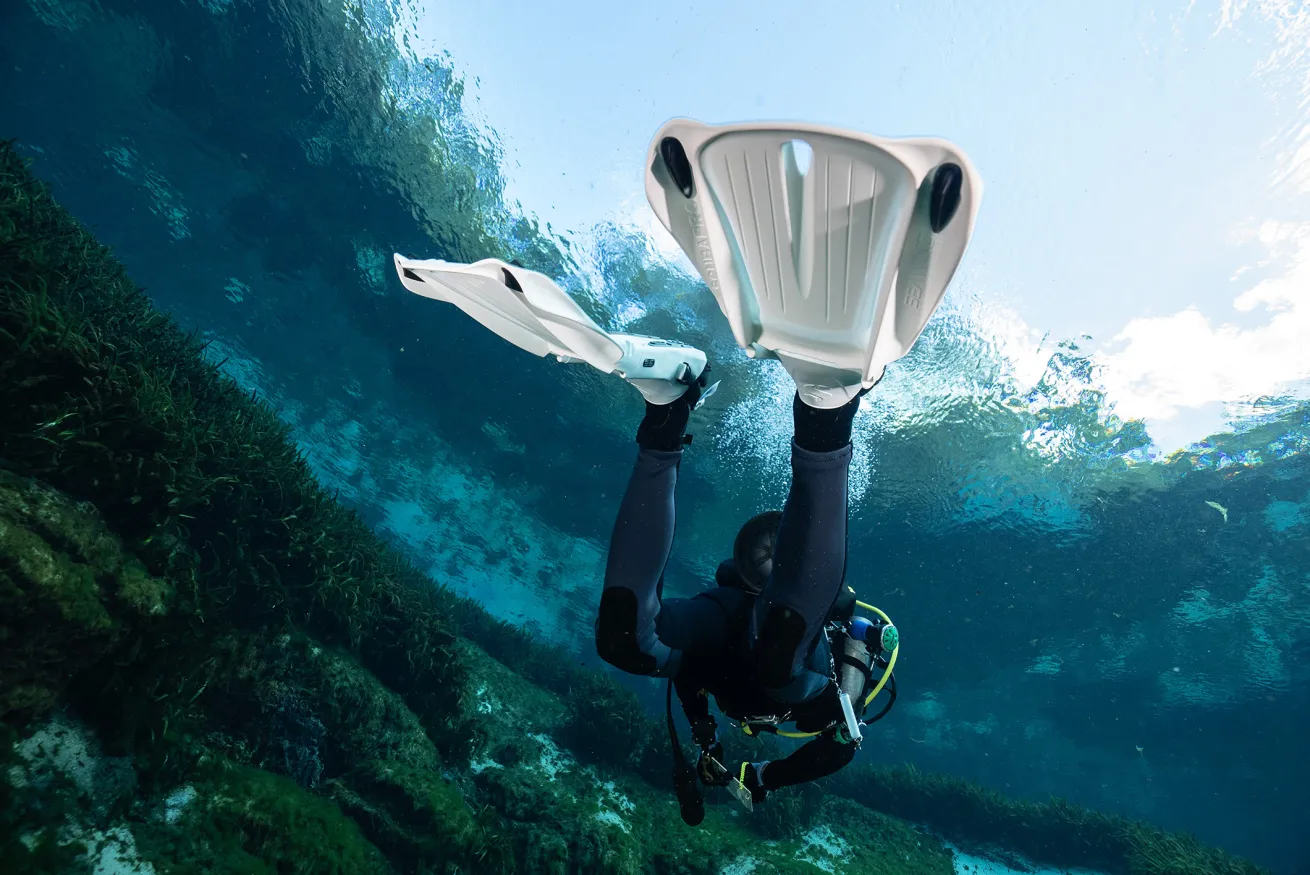 a diver underwater wearing white fins