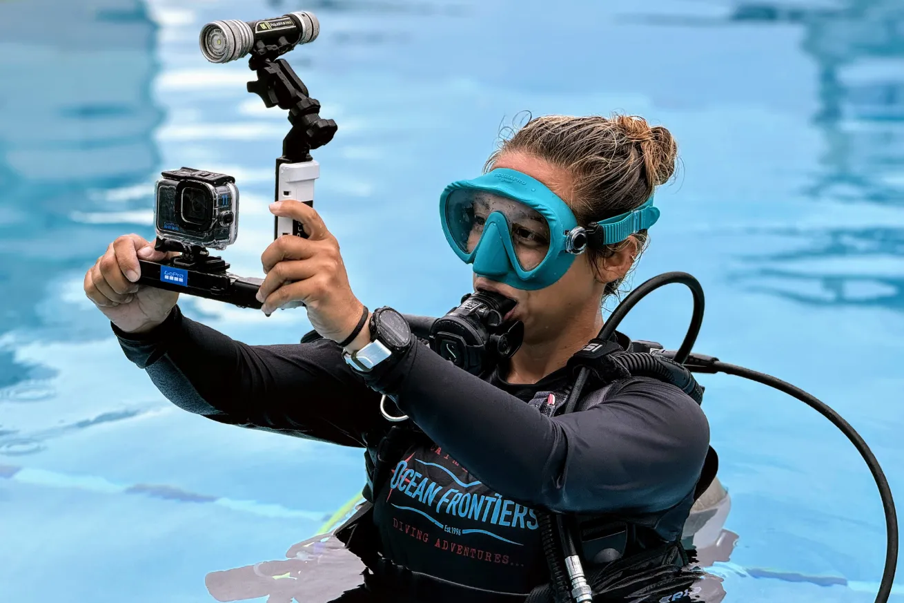 A person in a scuba diving suit holding a camera