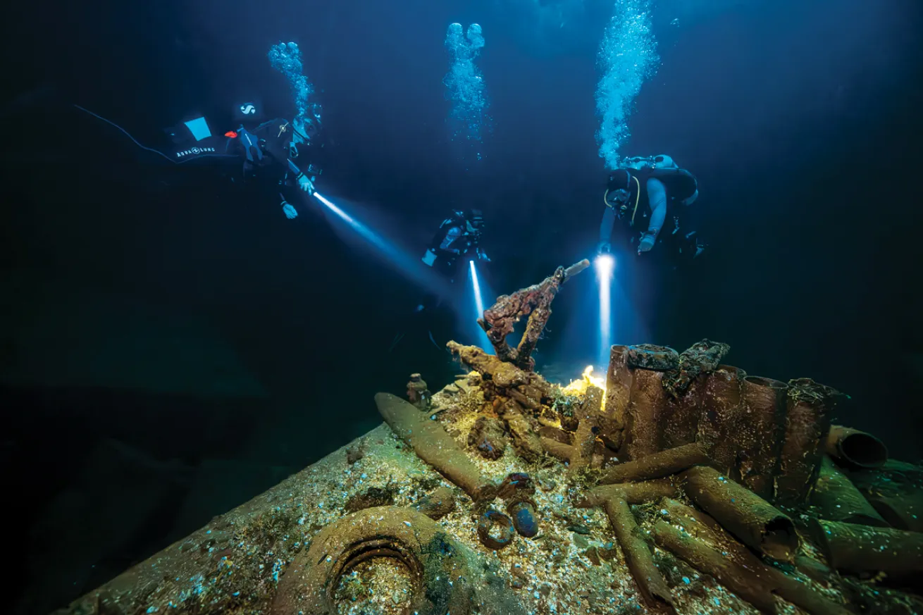 scuba divers  inspect artifacts of war inside the hold of *Fujikawa Maru*.