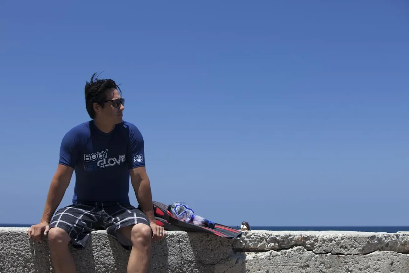 Diver sitting on wall by beach 