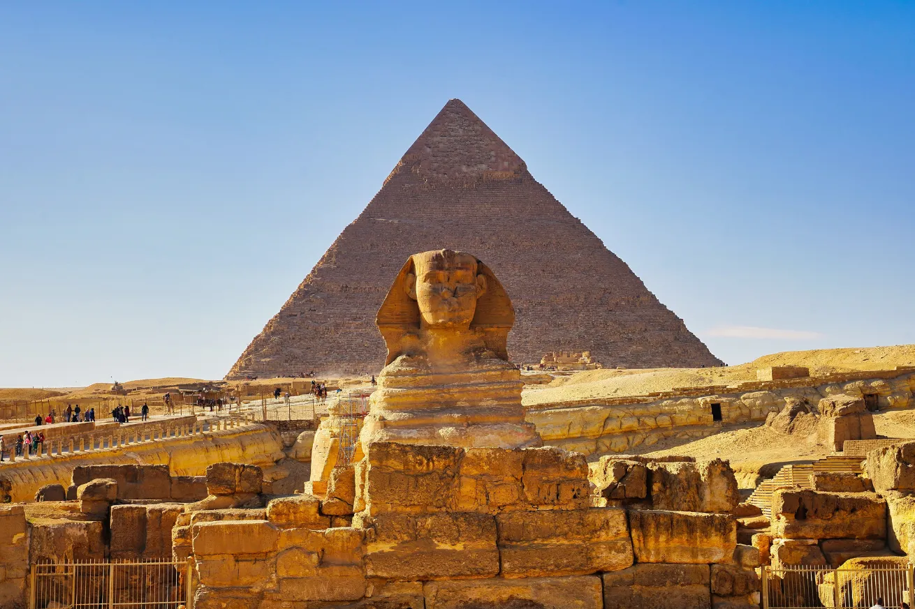 A statue of a sphinx in front of a pyramid