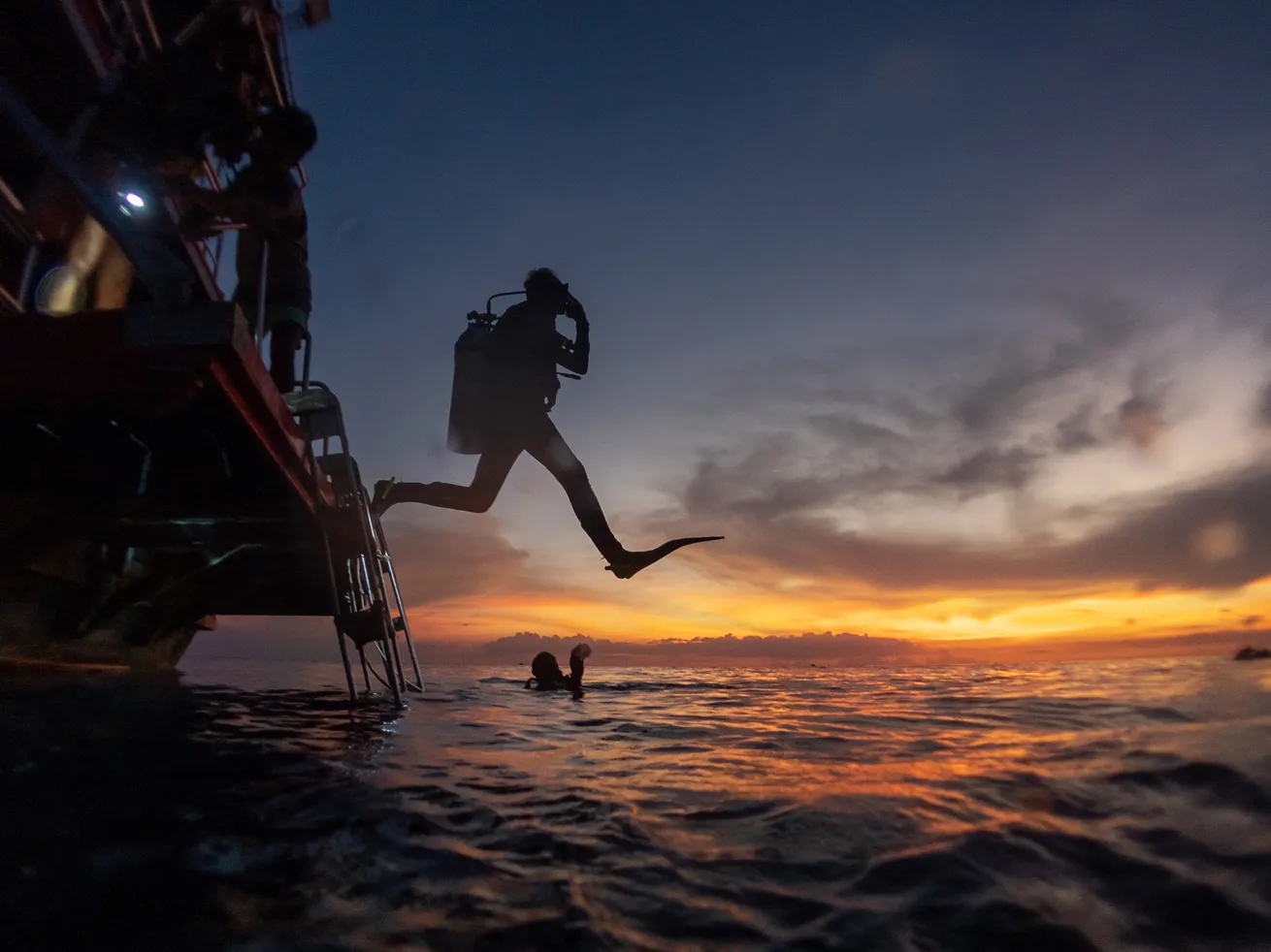 image of a diver entering the water at sunrise 