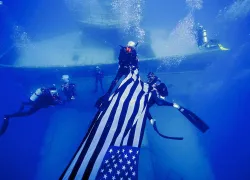 Divers carrying flag near shipwreck